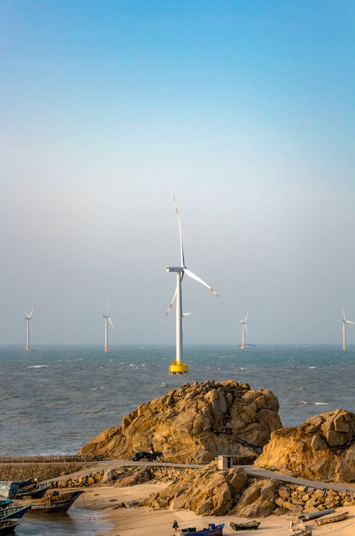 Scenic view of offshore wind turbines by a rocky coastline, showcasing sustainable energy.