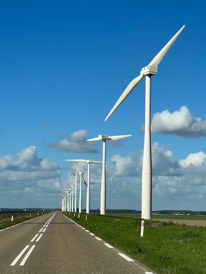 Scenic view of wind turbines lining an empty road under a blue sky in FL, Netherlands.